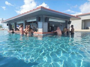 A pool area with a covered seating area and a building with speakers.