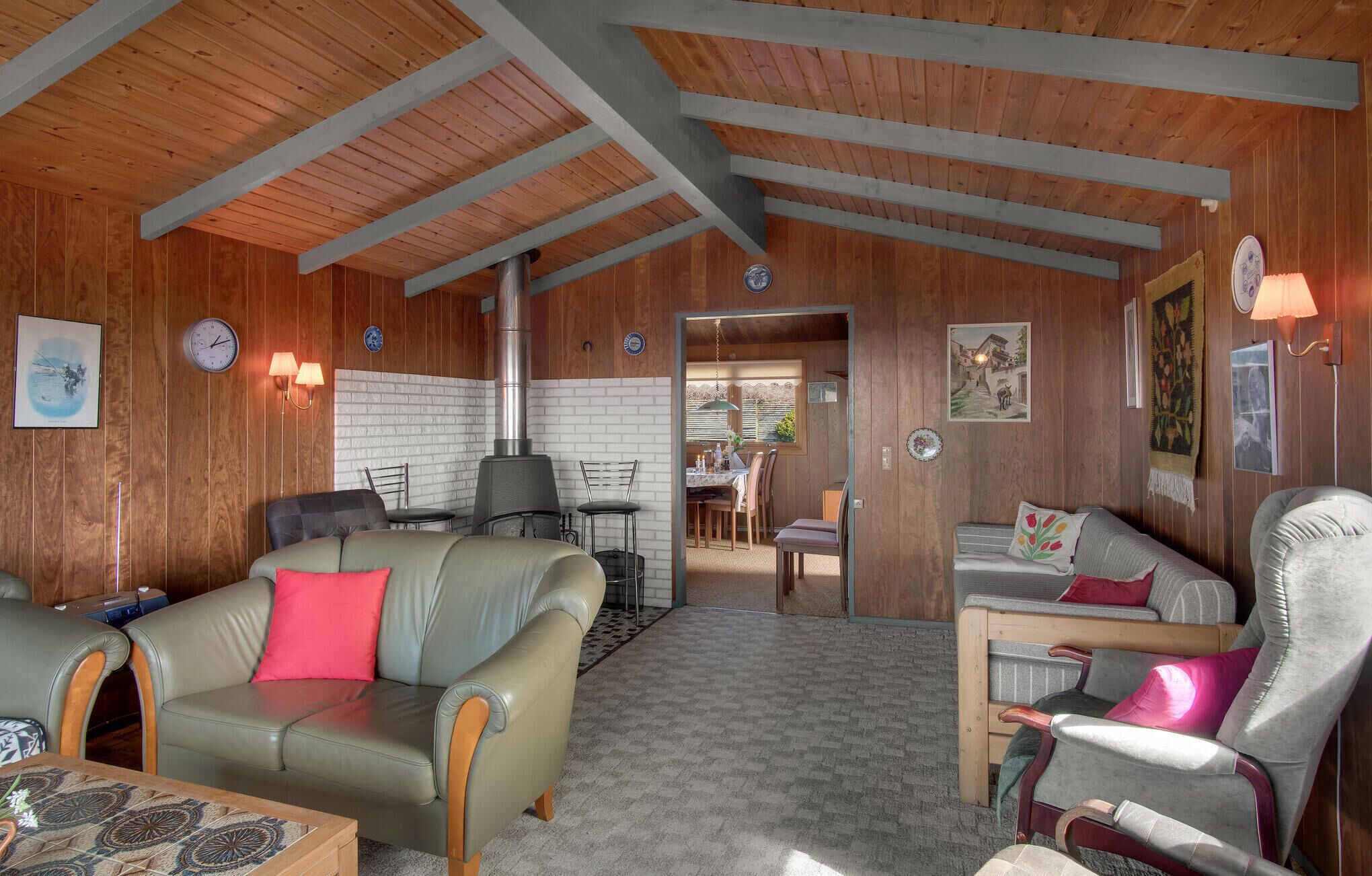 Una habitación acogedora con paredes y techo de madera, una chimenea, sofás de cuero y un comedor.