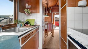A compact kitchen with a sink, countertop, and a dining area with a table and chairs. - 1 bedroom awesome home in Kalundborg (Kalundborg)