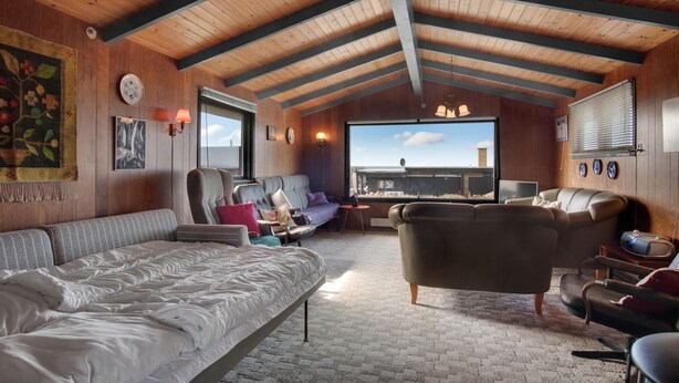 A cozy room with a high ceiling, wooden beams, a large window with a view, a sofa, a chair, and a bed. - 1 bedroom awesome home in Kalundborg (Kalundborg)