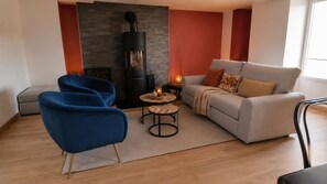 A modern living room with a sofa, a blue chair, a round coffee table, and a fireplace.