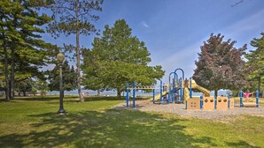 Un parque infantil con estructuras para escalar y un tobogán, rodeado de césped y árboles.