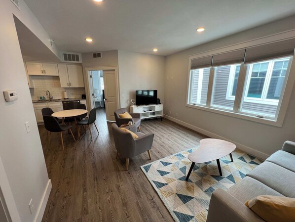 Un appartement moderne comprenant un coin repas, un salon et une kitchenette.