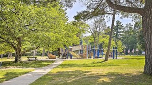 Un parque con un área de juegos, bancos y un sendero para caminar.