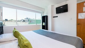 A hotel room with a large bed, a TV mounted on the wall, and a window with a view of buildings. - Ayenda 1067 Bogota Elite (Bogotá)