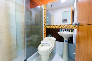 A bathroom with a glass-enclosed shower, a toilet with a white towel, a sink, and a mirror. - Ayenda 1067 Bogota Elite (Bogotá)