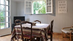 Une salle à manger avec une table dressée pour quatre personnes, un téléviseur et une fenêtre avec des rideaux.