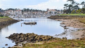 Un port de plaisance avec des bateaux amarrés, une côte rocheuse et des bâtiments en arrière-plan.