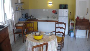 Une cuisine de taille réduite comprenant une table à manger, des chaises, un réfrigérateur et un four à micro-ondes.