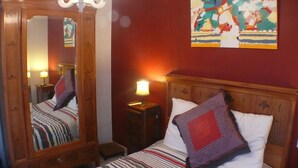 Une chambre d’hôtel avec un grand miroir, un lit avec une literie à rayures, une table de chevet avec une lampe et une peinture abstraite aux couleurs vives accrochée au mur.