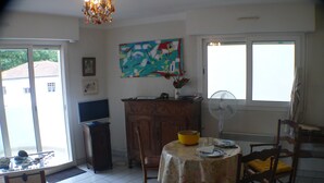 Un coin repas avec une table dressée pour deux personnes, un téléviseur et un tableau accroché au mur.