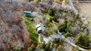 An aerial view of a rural property with a main house, a barn, and a driveway.