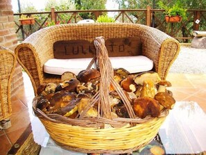 A wicker basket filled with mushrooms on a table in an outdoor setting. - Agriturismo L'uliveto (Reitano)