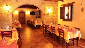 A restaurant with stone walls, wooden beams, and tables set with yellow tablecloths and red napkins. - Agriturismo L'uliveto (Reitano)