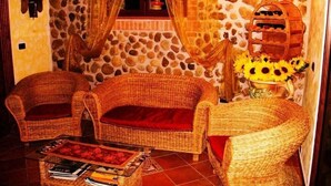 Um quarto aconchegante com móveis de vime, parede de pedra e janela com cortinas.