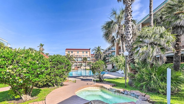 A resort pool area with a wooden deck, a small hot tub, and a view of the hotel buildings in the background. - Steps to Galveston Beach: Resort-Style Condo! (Galveston)
