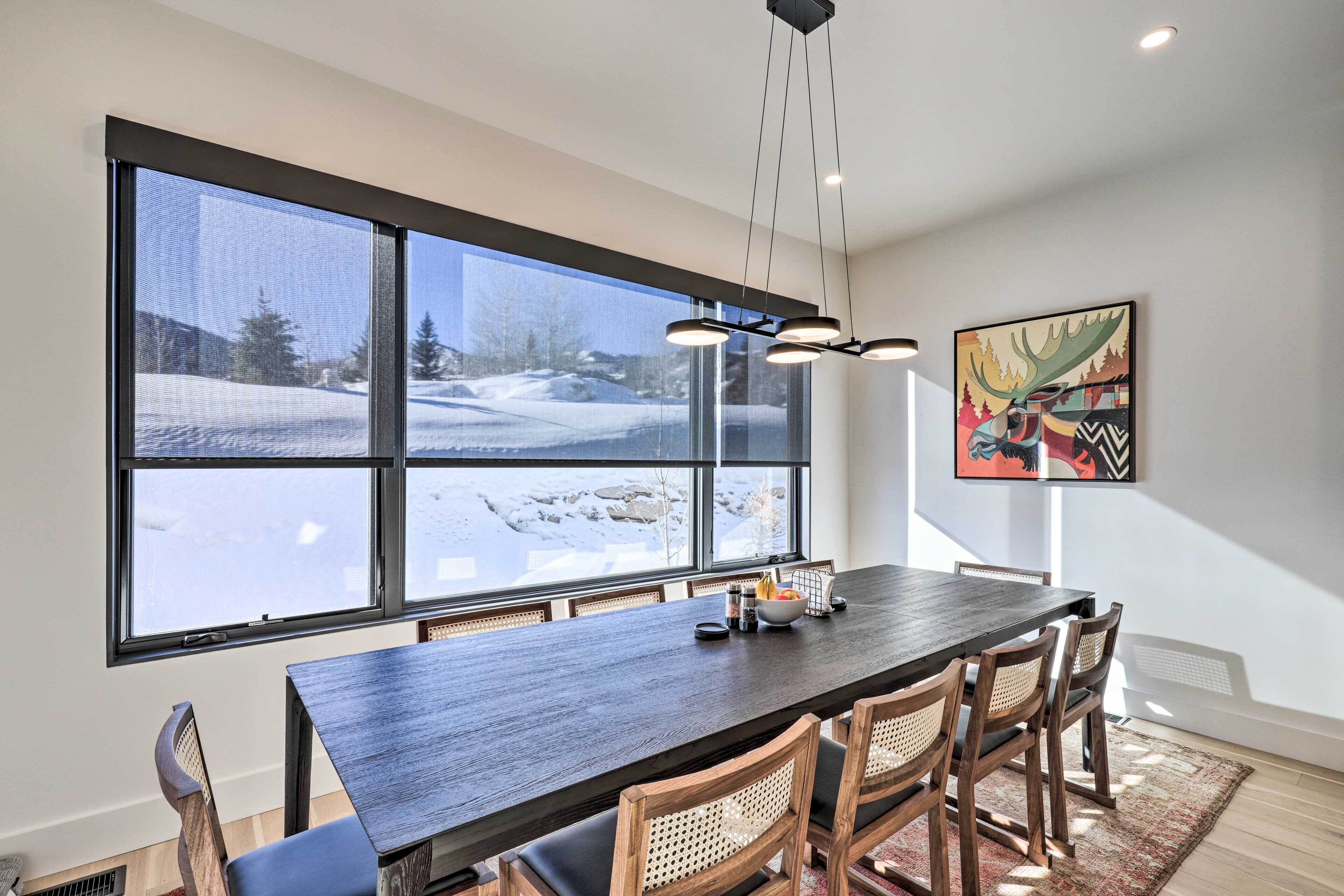 A dining area with a large window, a dark wooden table, and several chairs.