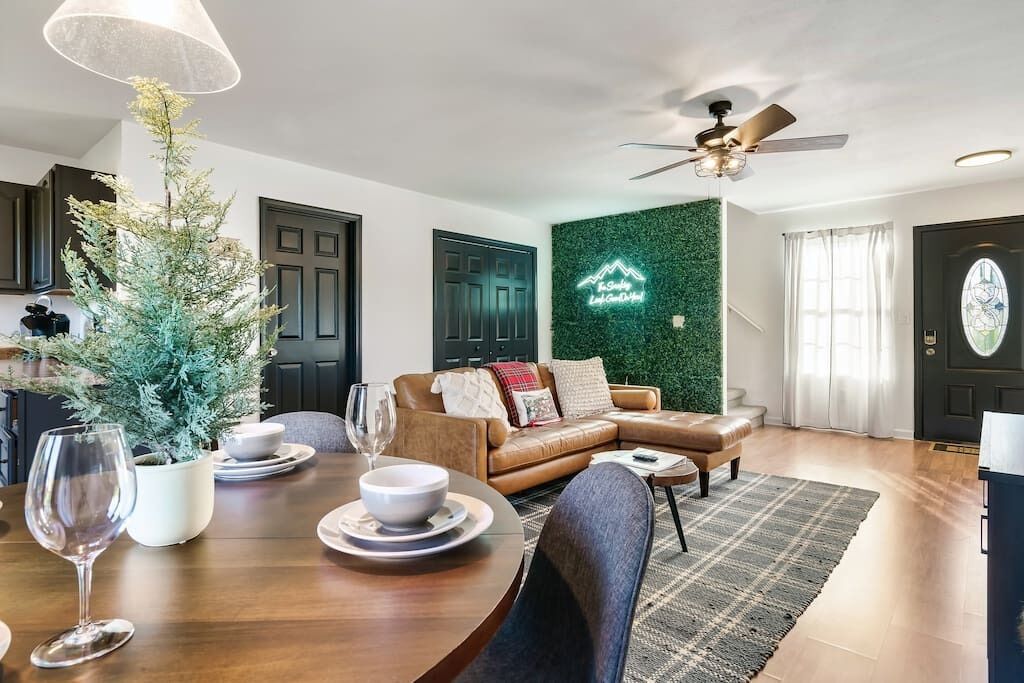 A modern living room with a dining table set for two, a sofa, and a decorative plant.