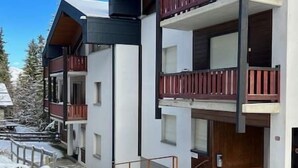 A multi-story building with balconies, a staircase, and a snow-covered ground.
