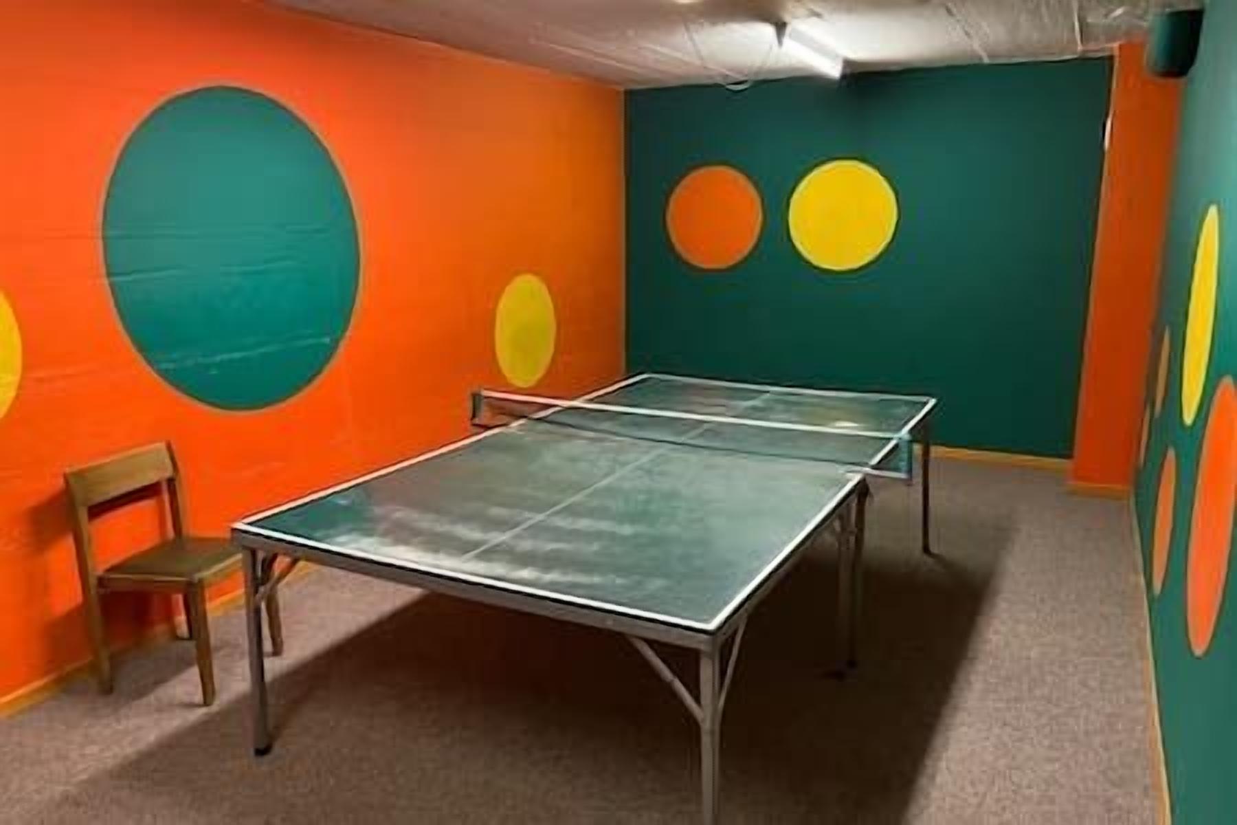 A ping pong table in a room with colorful wall art.