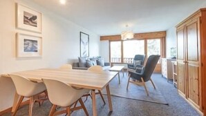 A room with a long wooden table, two chairs, a sofa, and a cabinet.