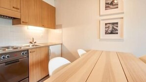 A modern kitchen with wooden cabinets, a stainless steel stove, and a white dining table.