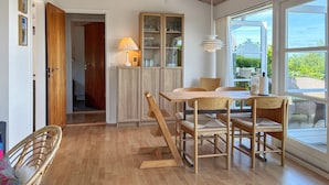 A dining area with a wooden table and chairs, a cabinet with glass doors, and a view through large windows. - Nice home in Børkop with WiFi (Børkop)
