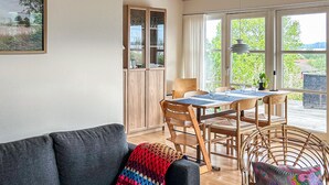 A cozy living room with a sofa, a dining table with chairs, a wicker chair, and a cabinet with glass doors. - Nice home in Børkop with WiFi (Børkop)