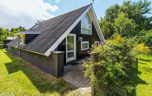 Een modern huis met een schuin dak, grote ramen en een klein portaaltje.