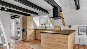 Une cuisine moderne avec des meubles en bois, un îlot central et une grande fenêtre qui laisse entrer la lumière naturelle.