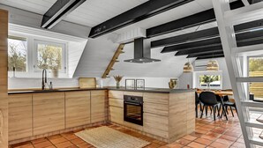 Une cuisine moderne dotée d’un îlot central en bois, d’un four encastré et d’une hotte noire.