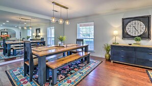 A dining area with a wooden table, benches, hanging light fixtures, and a patterned rug. - Sunny Florida Abode - Patio, Pool, & Fire Pit (Marianna)
