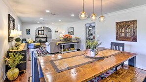 A spacious dining area with a wooden table, hanging pendant lights, and a view into the kitchen. - Sunny Florida Abode - Patio, Pool, & Fire Pit (Marianna)
