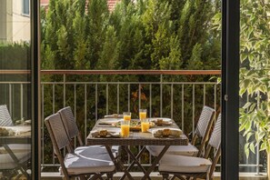 An outdoor dining area with a table set for four, surrounded by wicker chairs, and a view of dense greenery in the background. - Comboio I, comfort in the centre of Funchal. (Funchal)