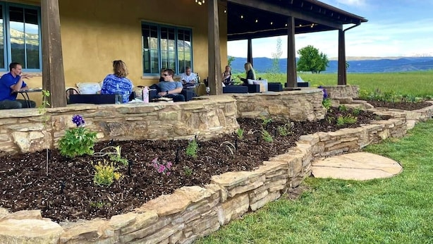 A covered outdoor seating area with stone walls and a stone pathway. - Violet Cottage at Zenzen Gardens (Paonia)