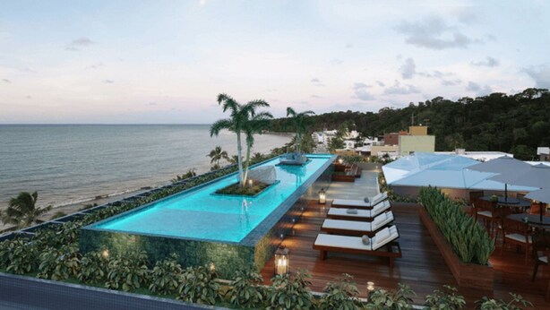 Piscina infinita no terraço com vista para o oceano, assentos em deck de madeira e guarda-sóis.