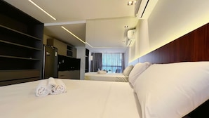 Quarto de hotel com cama grande, escrivaninha, guarda-roupa e espelho.