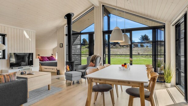 A spacious living area with a large window, a fireplace, and a dining table with chairs. - Pet friendly home in Hjørring with WiFi (Hjørring)