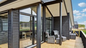 A modern outdoor deck with wicker furniture and a wooden floor, overlooking a grassy area. - Pet friendly home in Hjørring with WiFi (Hjørring)