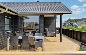 A covered outdoor area with a wooden deck, wicker furniture, and a view of the surrounding landscape. - Pet friendly home in Hjørring with WiFi (Hjørring)