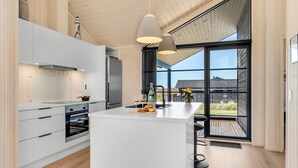 A modern kitchen with white cabinetry, a central island, and a large window offering a view of the backyard. - Pet friendly home in Hjørring with WiFi (Hjørring)
