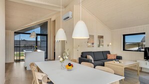 A modern, open-plan living space with a dining area, a sofa, and a TV. - Pet friendly home in Hjørring with WiFi (Hjørring)