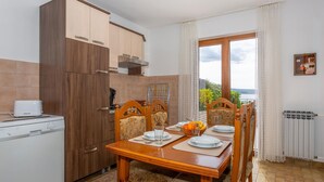 Cozinha compacta com eletrodomésticos modernos, mesa de jantar para quatro pessoas e vista para o exterior.