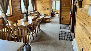 A cozy cabin interior with a dining area, a sofa, and a living room. - EAGLE LODGE - Large log cabin on the E. Fork of Chippewa River (Loretta)