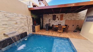 Une piscine dotée d’une terrasse en bois et d’un mur en pierre.