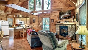 Una cabaña amplia con interior de madera, una chimenea de piedra y una zona de estar acogedora.