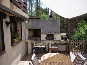 Eine Terrasse im Freien mit Holzofen, Holzmöbeln und einem Blumentopf.