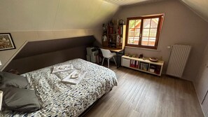 Ein Schlafzimmer mit einem Bett, einem Schreibtisch, einem Stuhl und einem Bücherregal.