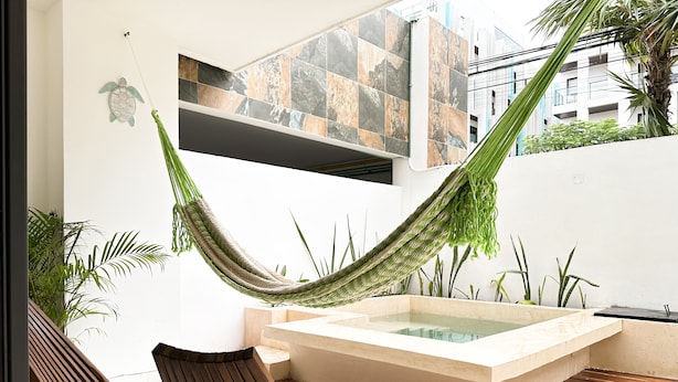 A hammock, a wooden bench, and a hot tub in a modern outdoor space. - Lovely condo w/private pool, 3 min from the beach! (Playa del Carmen)
