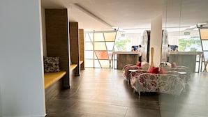A spacious room with a long bench, a sofa set, and a counter with a 'SALIDA' sign. - Lovely condo w/private pool, 3 min from the beach! (Playa del Carmen)